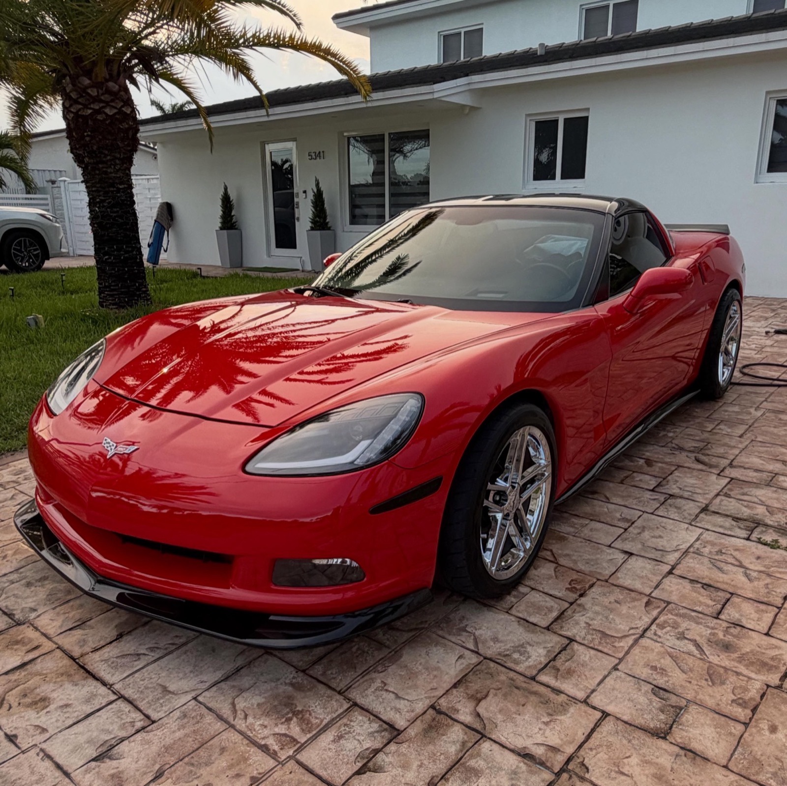 A glossy red Corvette freshly detailed in a Miami driveway